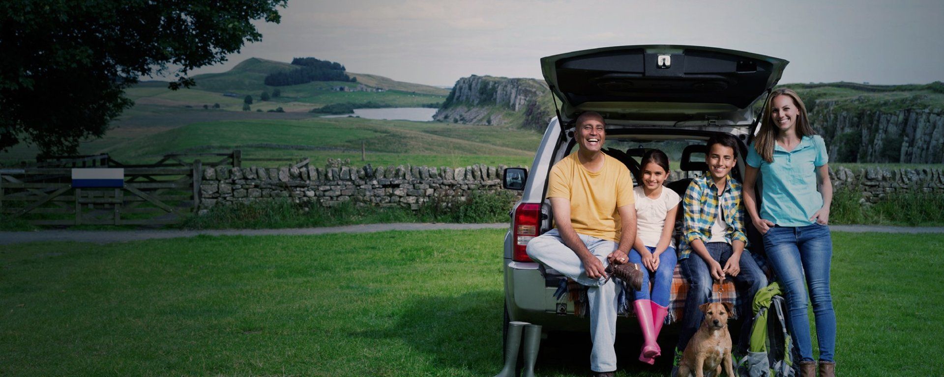 a family is sitting in the back of a car with a dog .