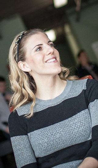 A woman in a striped sweater is smiling and looking up.