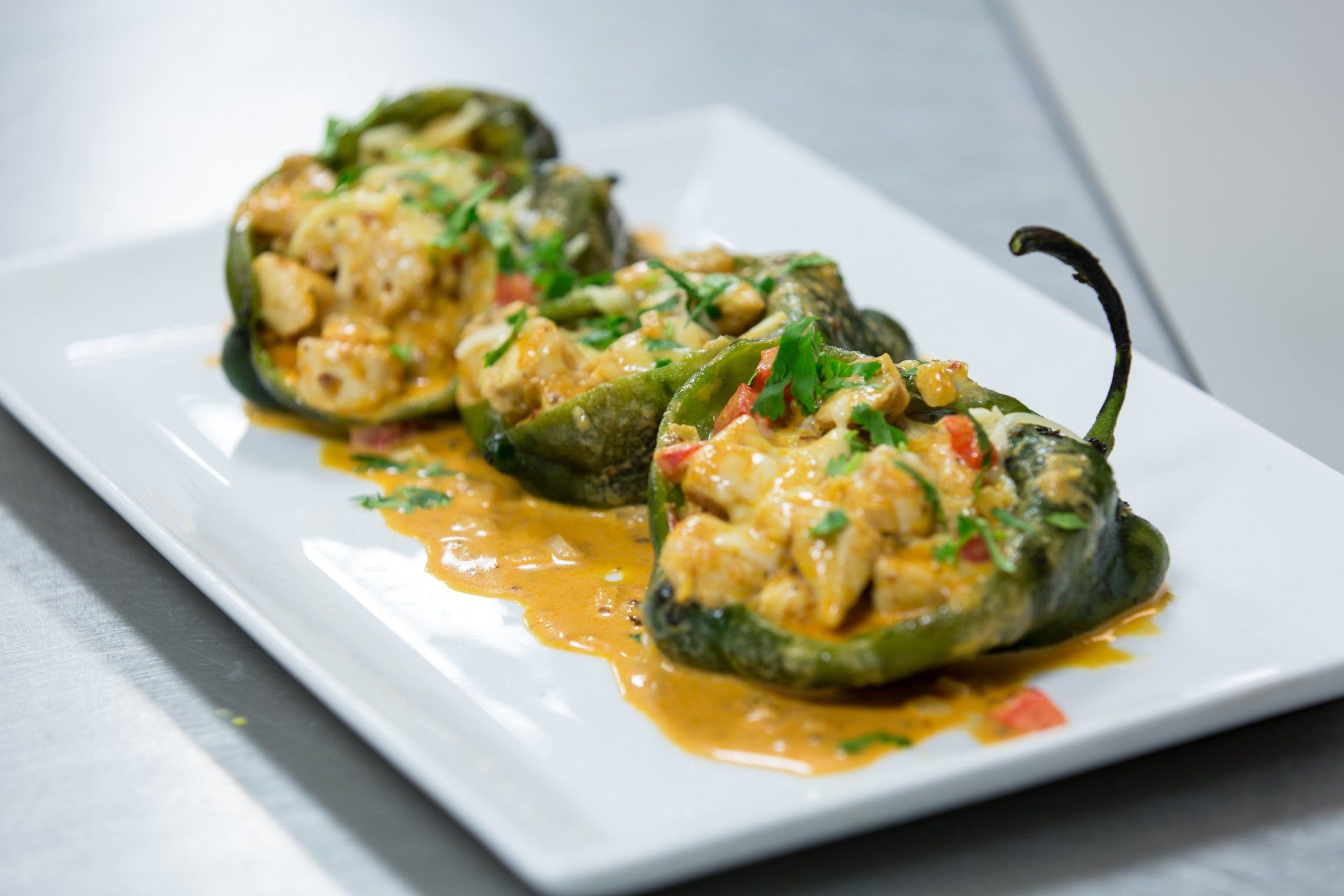 a white plate topped with stuffed peppers and sauce .