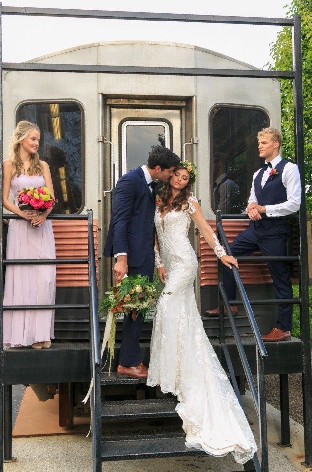 A bride and groom kissing on the steps of a train car.