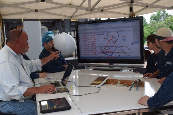 A group of people are sitting around a table looking at a computer screen