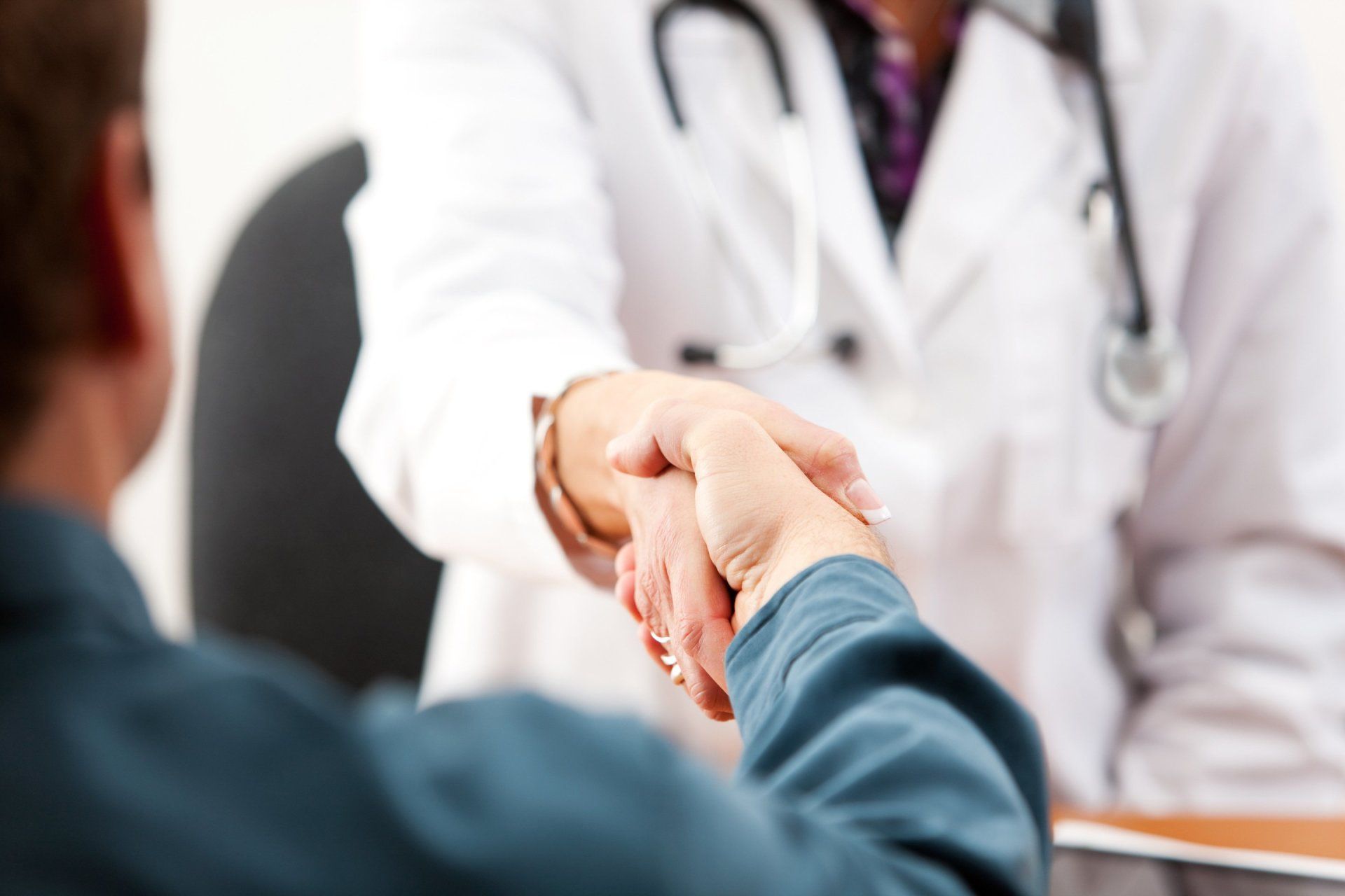 A doctor is shaking hands with a patient in a hospital.