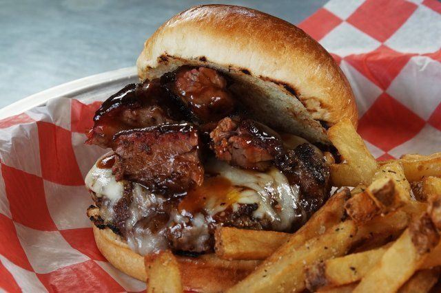 A hamburger and french fries in a basket on a checkered paper