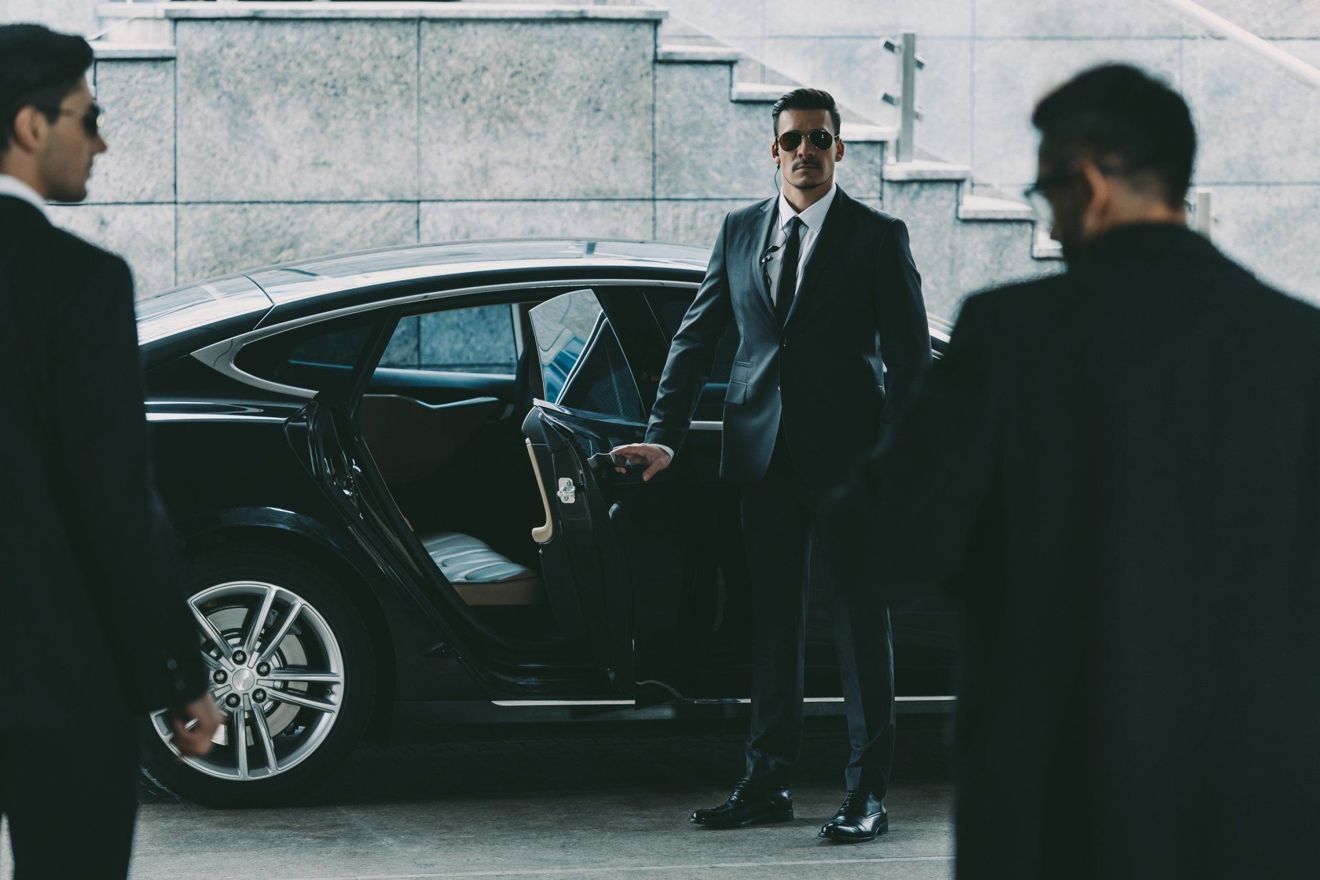 A man in a suit and tie is standing next to a car.