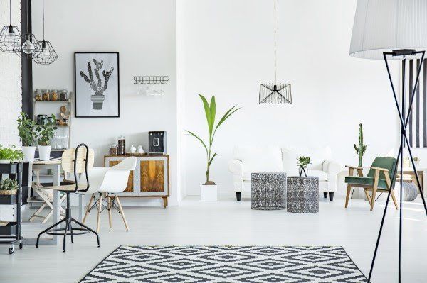 A living room with a rug , chairs , a table and a lamp.