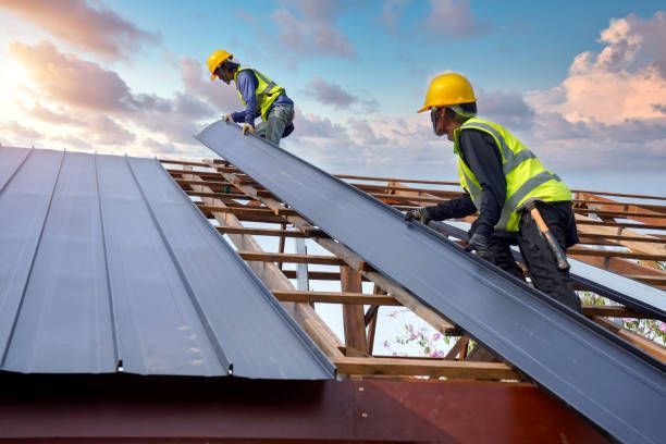 Roofing contractors installing durable metal roofing panels.