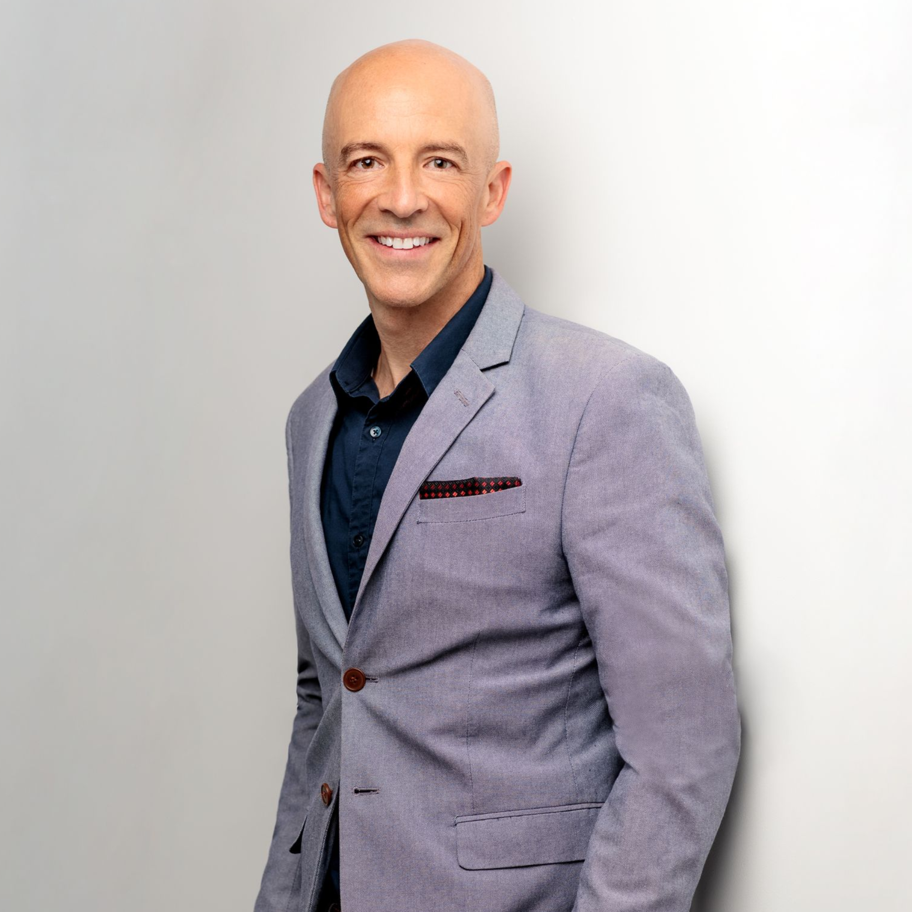 Michael Ceely in a suit smiles, with a gray background.