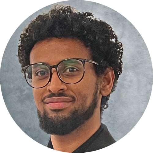 A smiling man with curly dark hair and glasses.