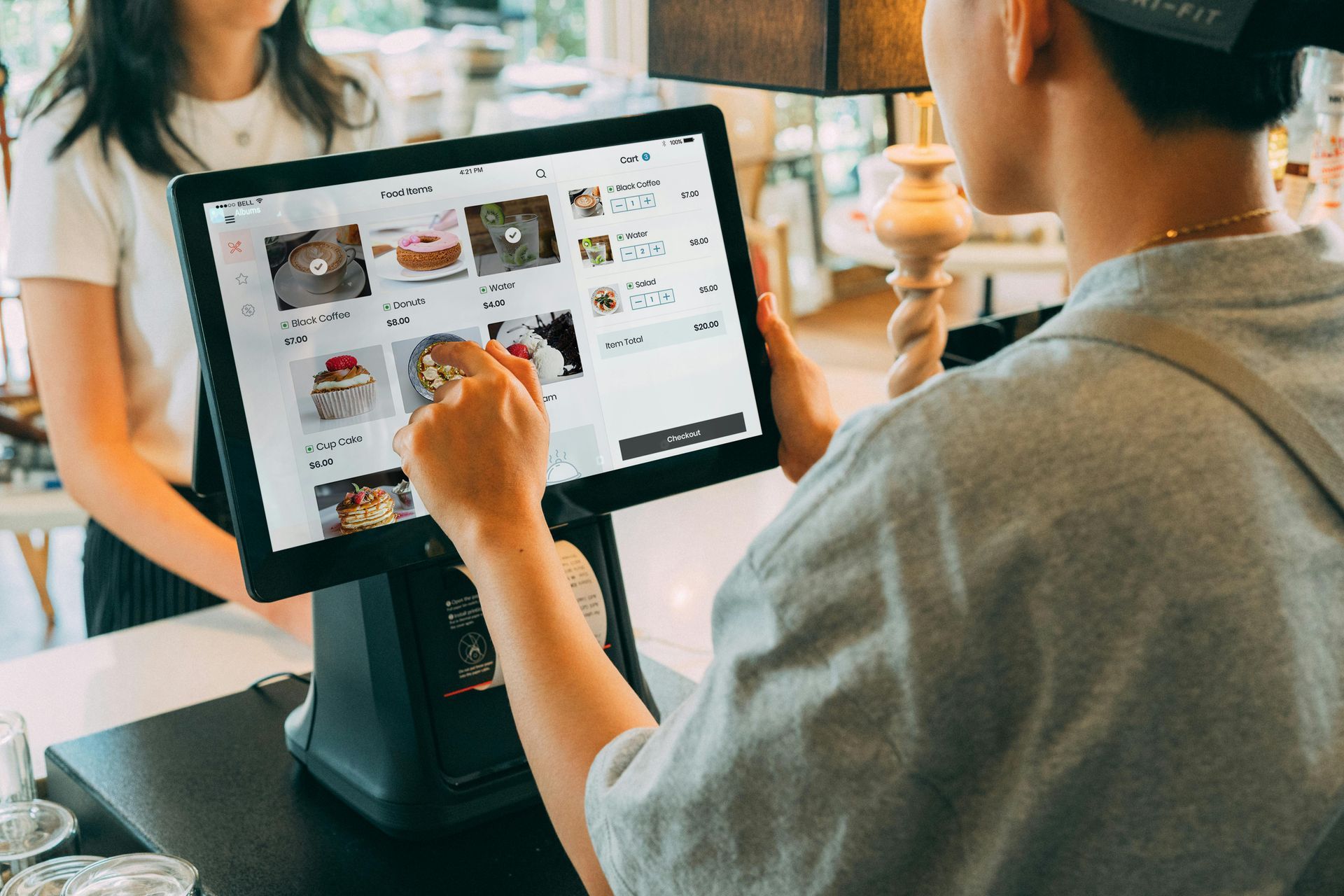 A person using a touchscreen point of sale system to ring up a customer in a shop.