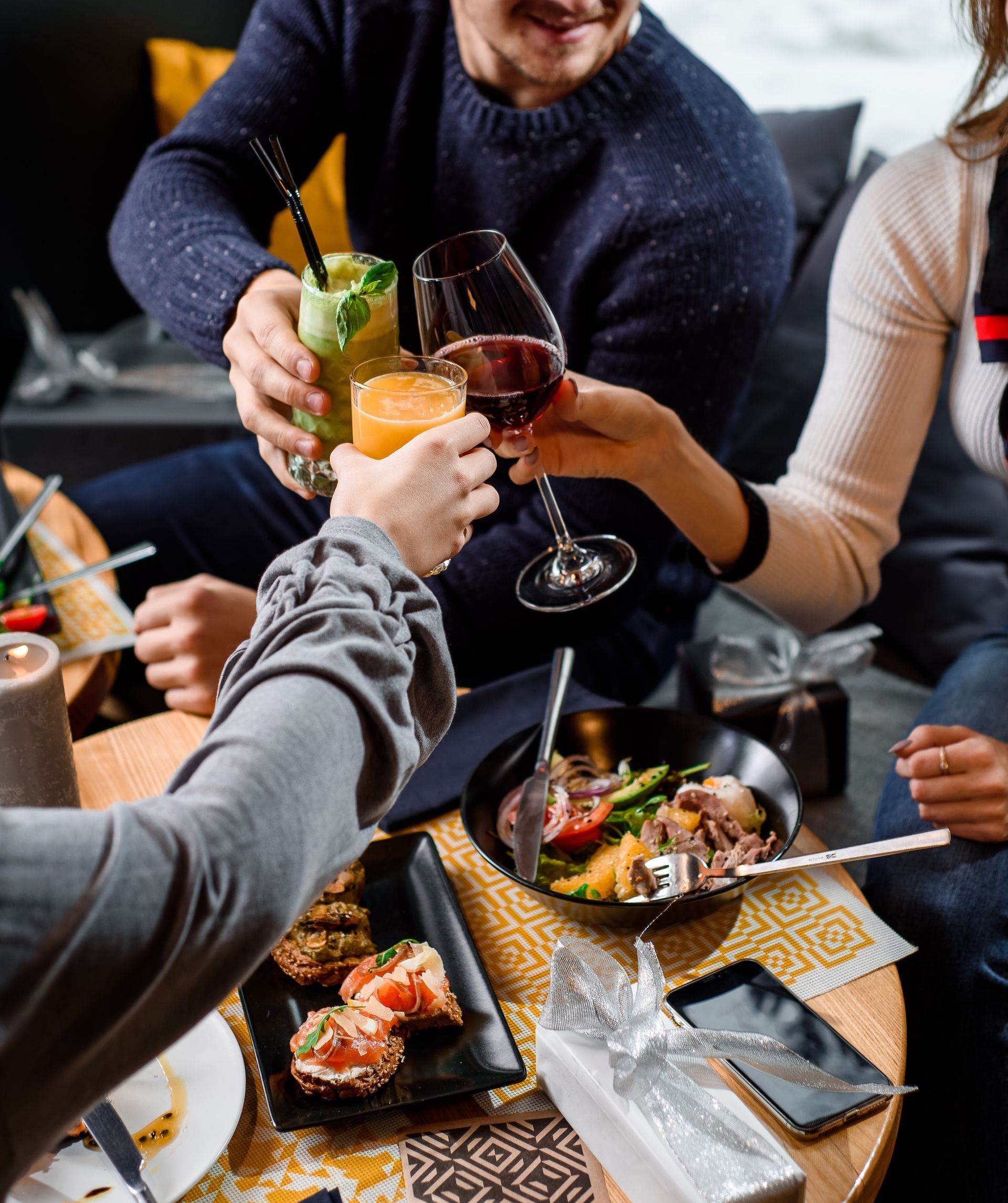 A group of people are sitting around a table eating food and drinking wine.