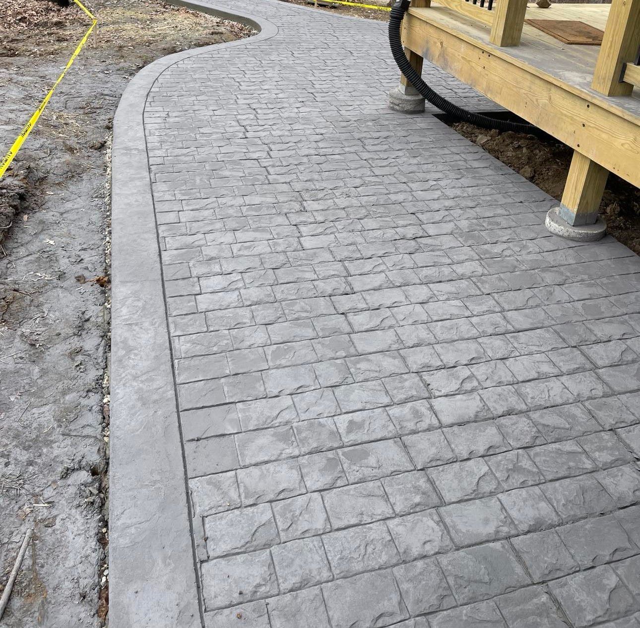 A concrete walkway is being built next to a wooden deck.