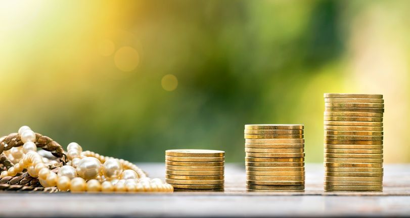 Gold coins and pearls on a table at Staples Jewelry, your trusted Gold and Silver Jewelry Buyers.