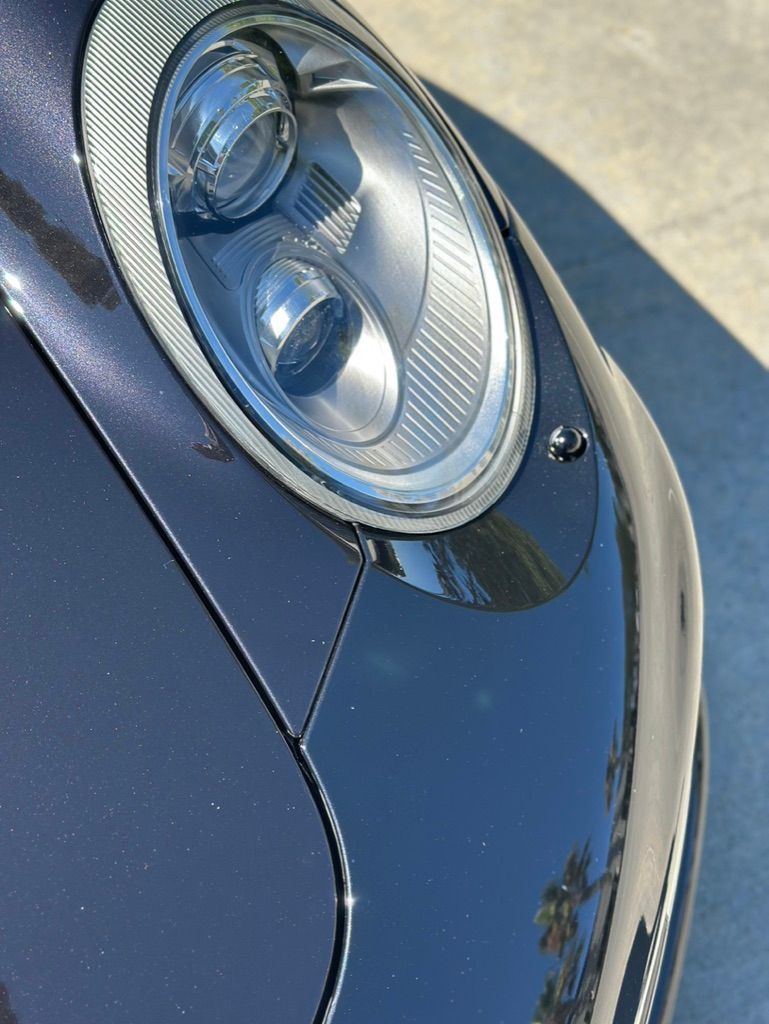 A man is applying a protective film to the headlights of a mercedes benz.
