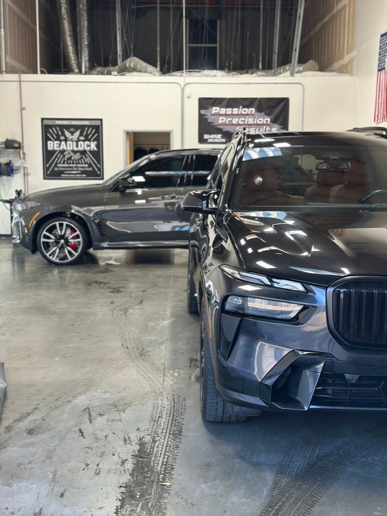 A man is applying protective film to the hood of a car.
