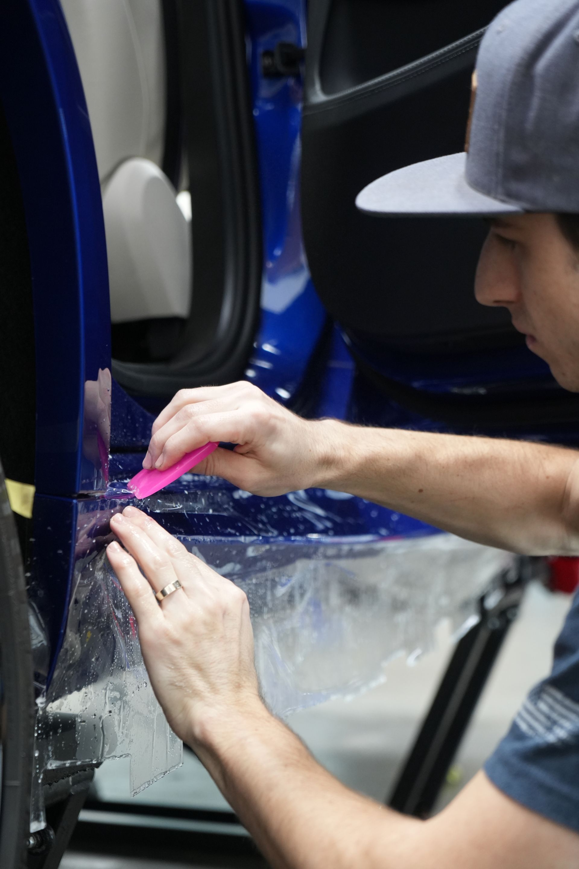 Person applying protective film to a car's side mirror, close up shot.