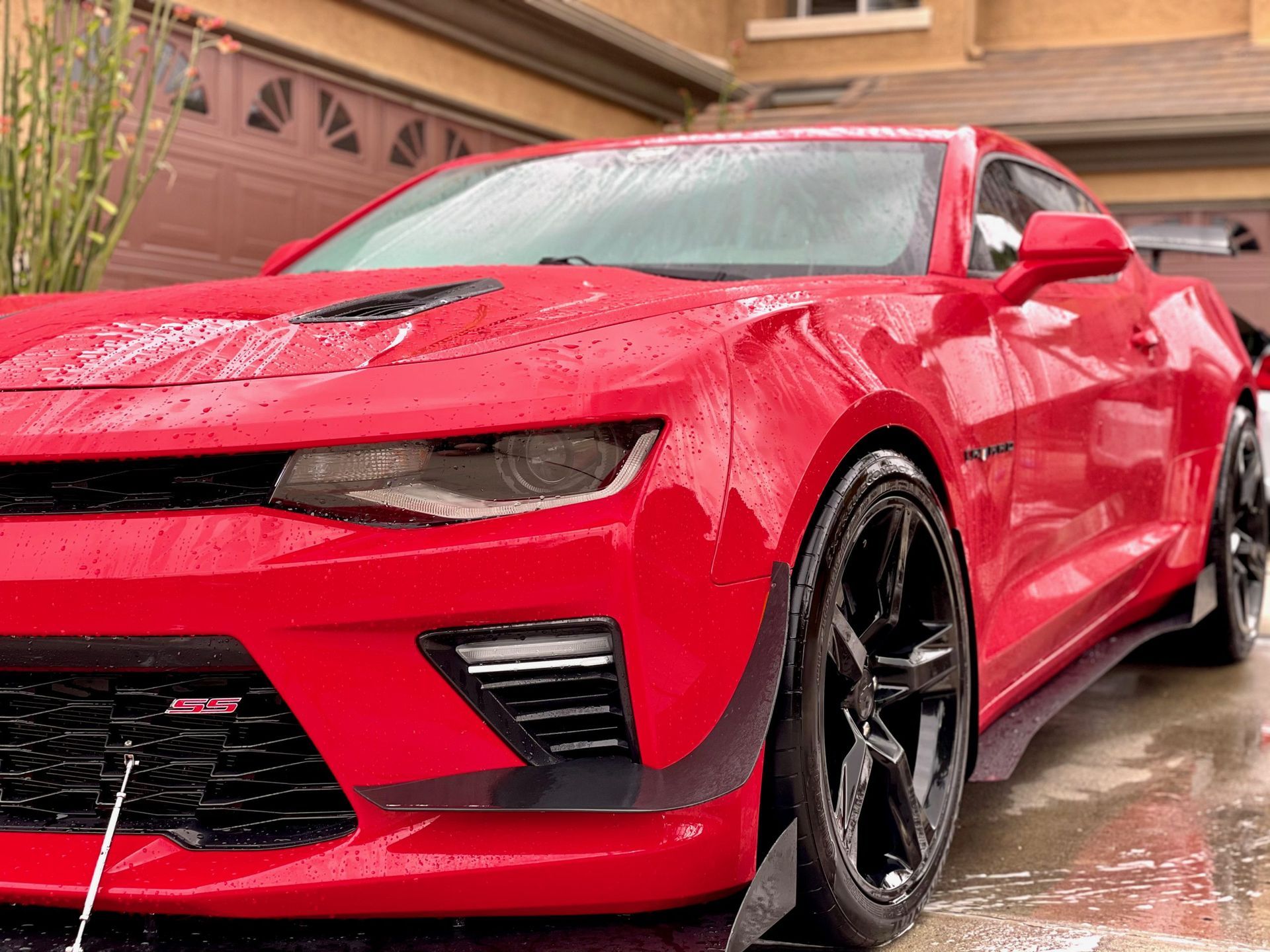 A red car is parked in front of a garage door.