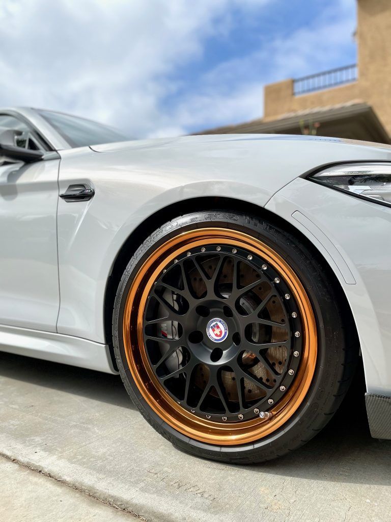 A silver bmw m2 is parked on the side of the road.