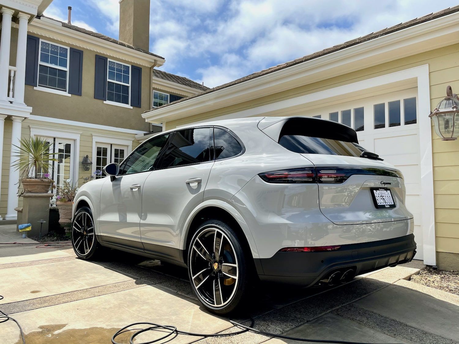 A silver porsche cayenne is parked in front of a house.
