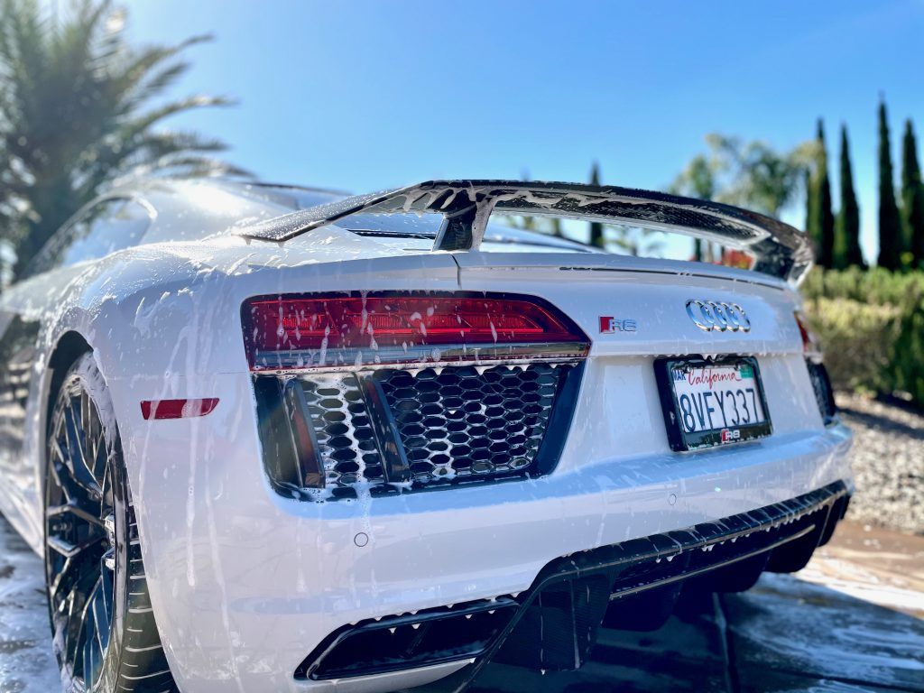 A white audi r8 is being washed with soap and water.