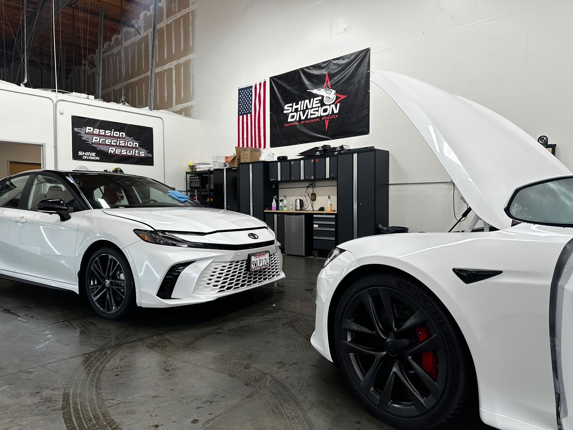 Close-up of a green car panel with light gray primer showing through the paint. Foam is visible.
