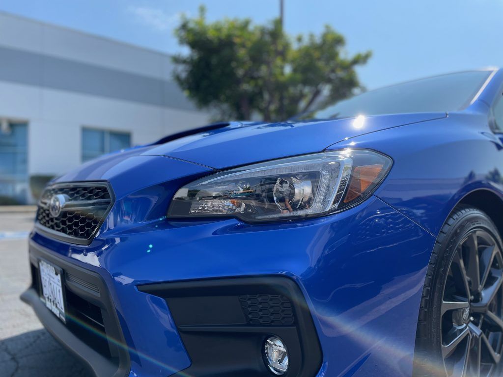 A blue subaru wrx sti is parked in front of a building.