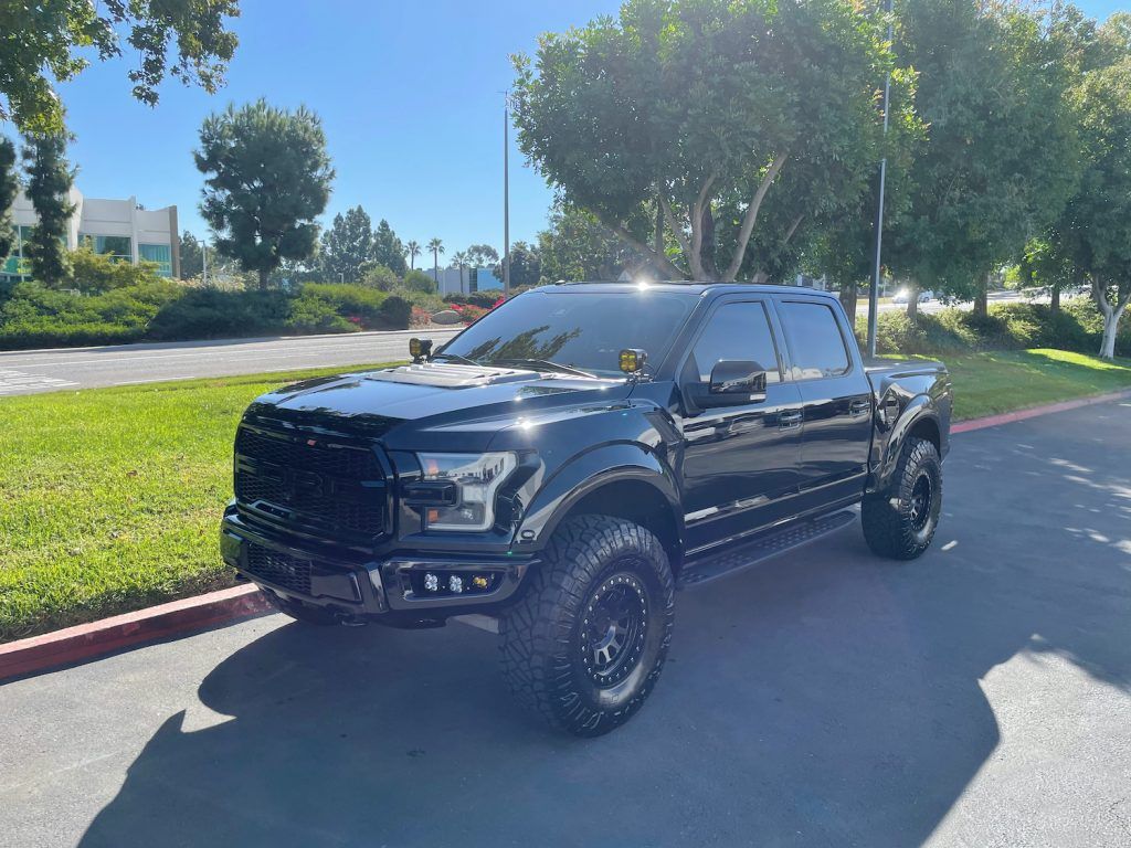 A black ford f150 raptor is parked in a parking lot.