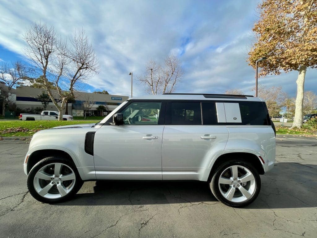 A white land rover defender is parked in a parking lot.