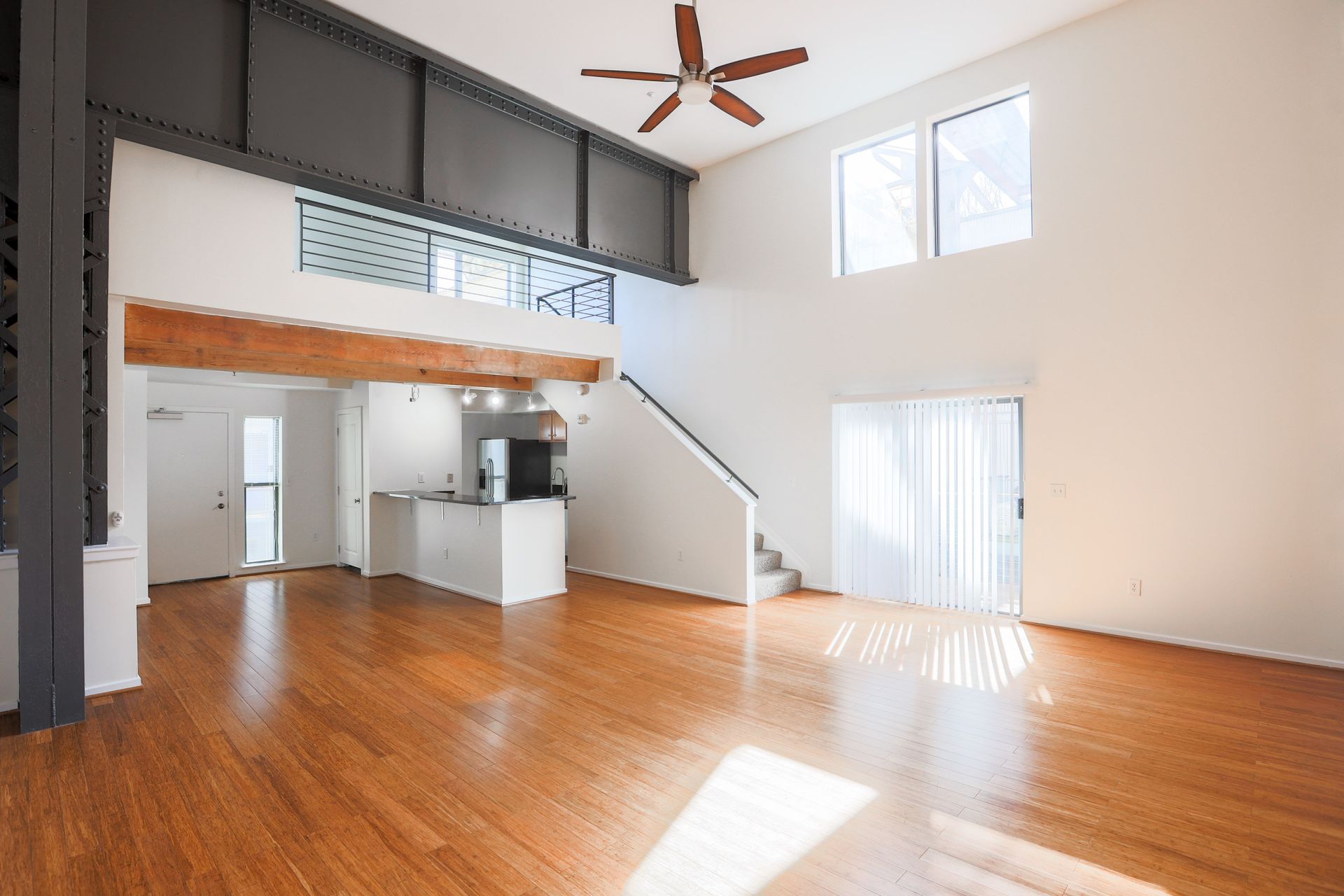 a large empty room with hardwood floors and a ceiling fan .