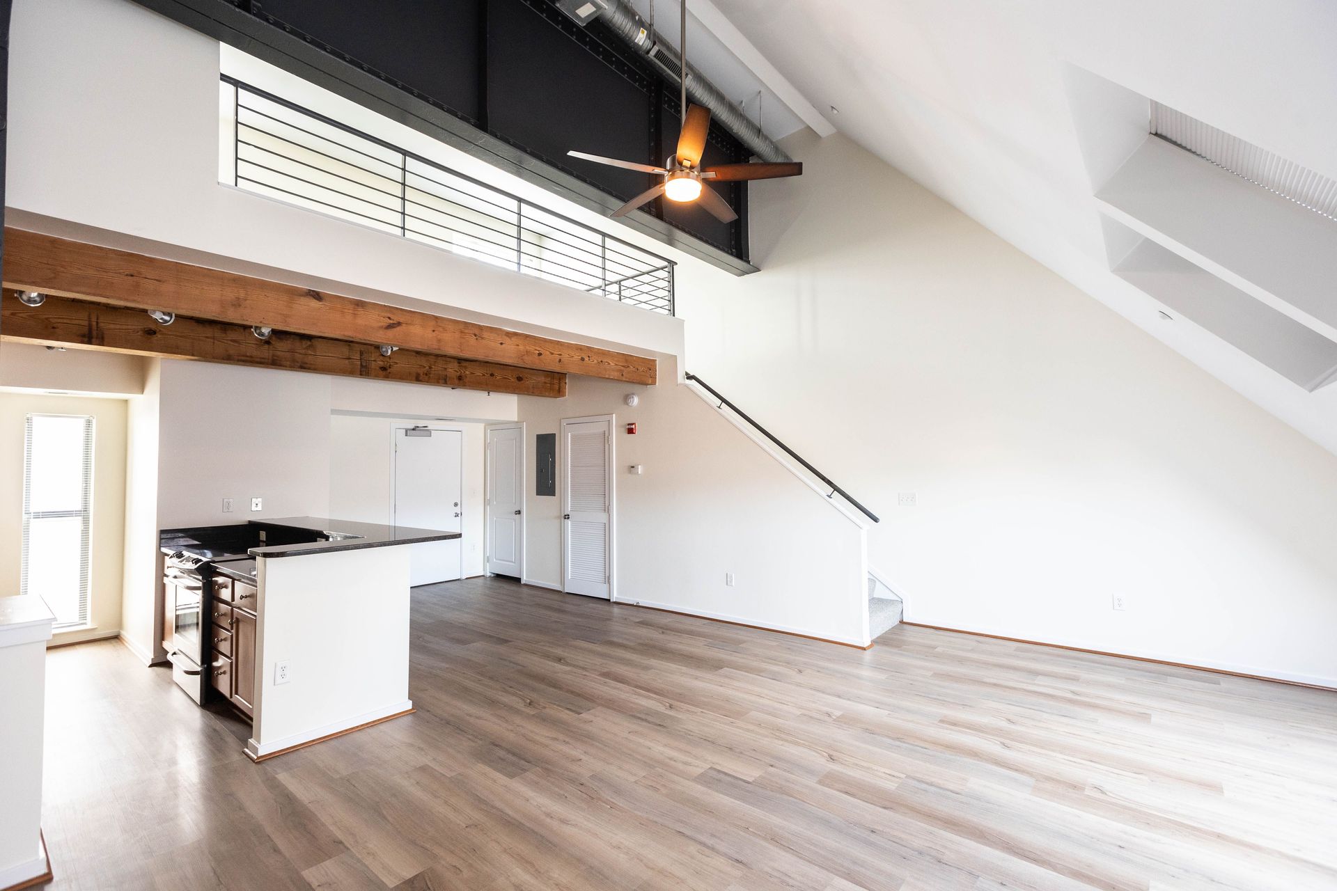 a large empty room with a ceiling fan and stairs .