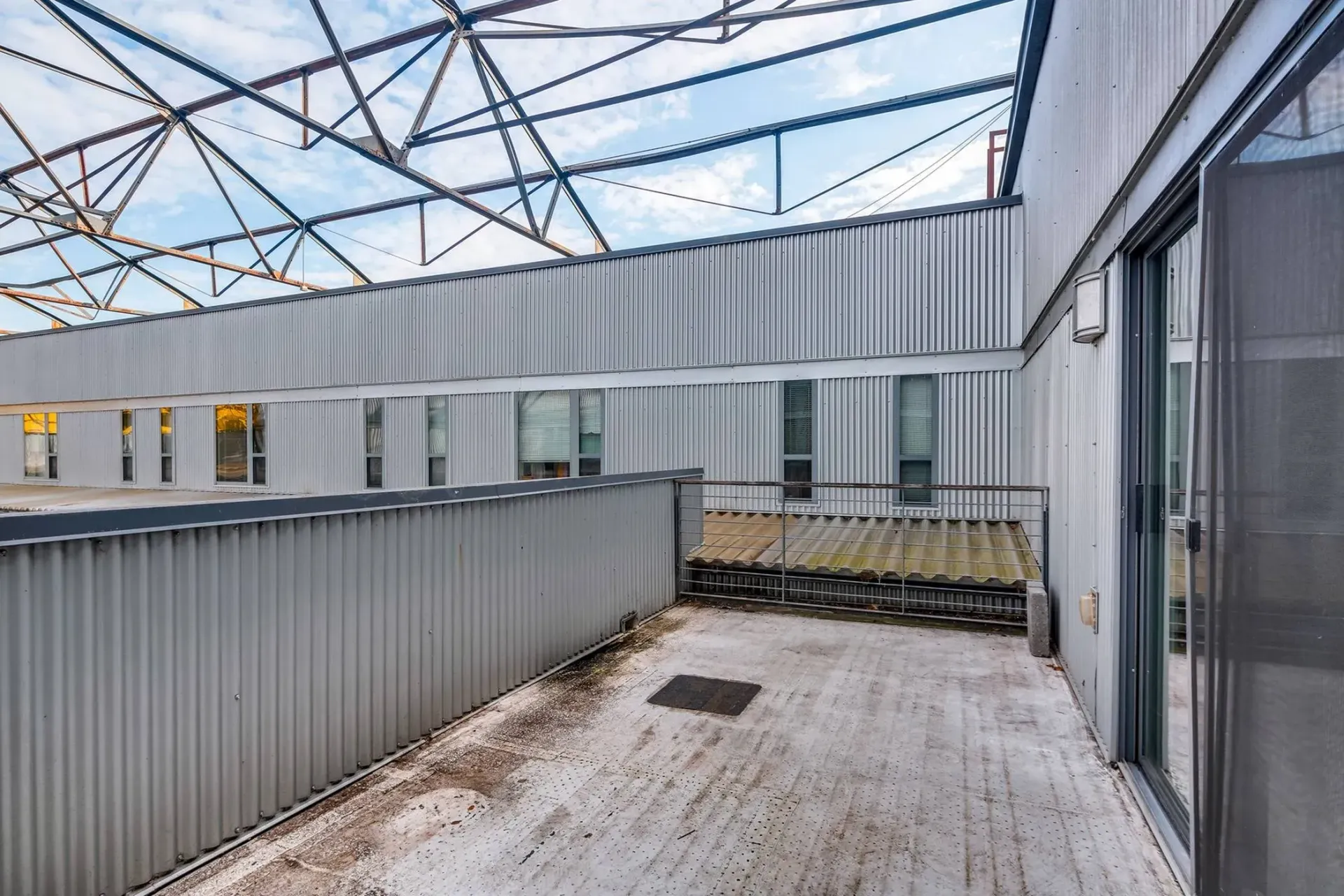 a balcony with a fence and sliding glass doors in a building .