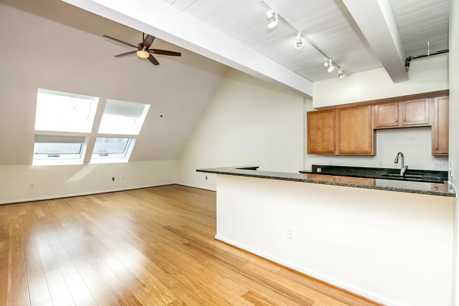 an empty kitchen with hardwood floors and a ceiling fan