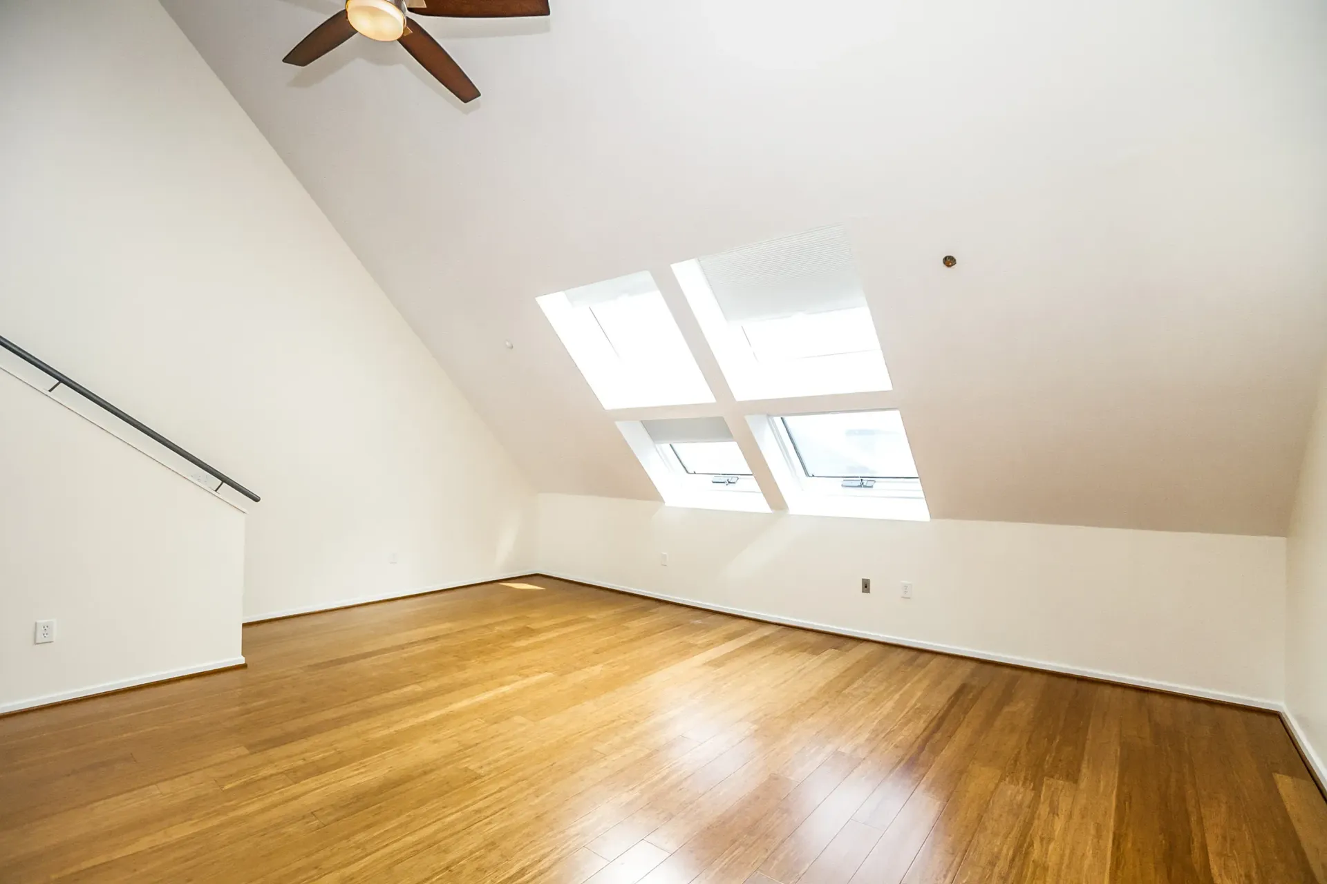 an empty room with ceiling fan and wooden floors