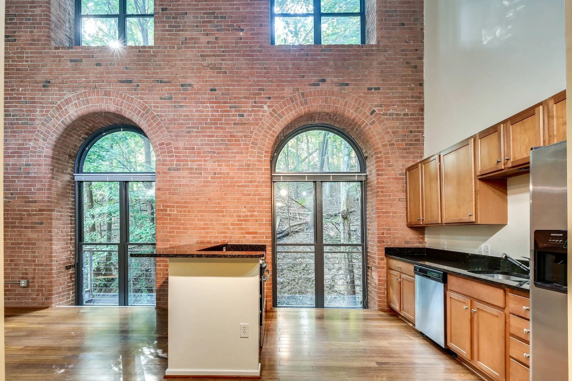 an empty kitchen with brick walls and arched windows