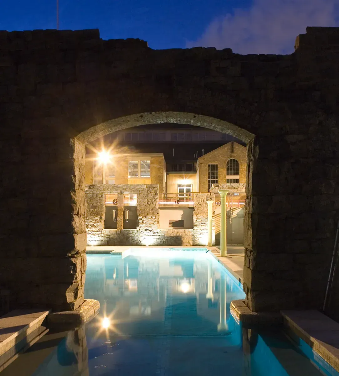 a large swimming pool is lit up at night