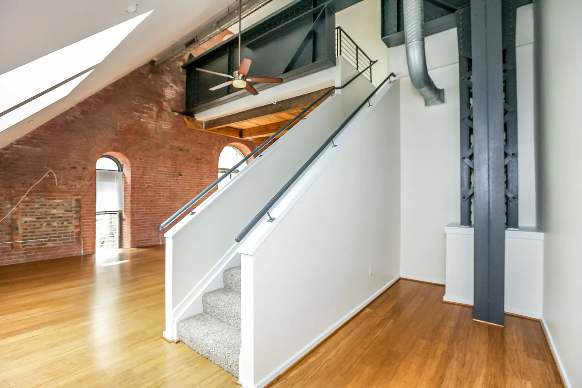 an empty room with a staircase and a ceiling fan .