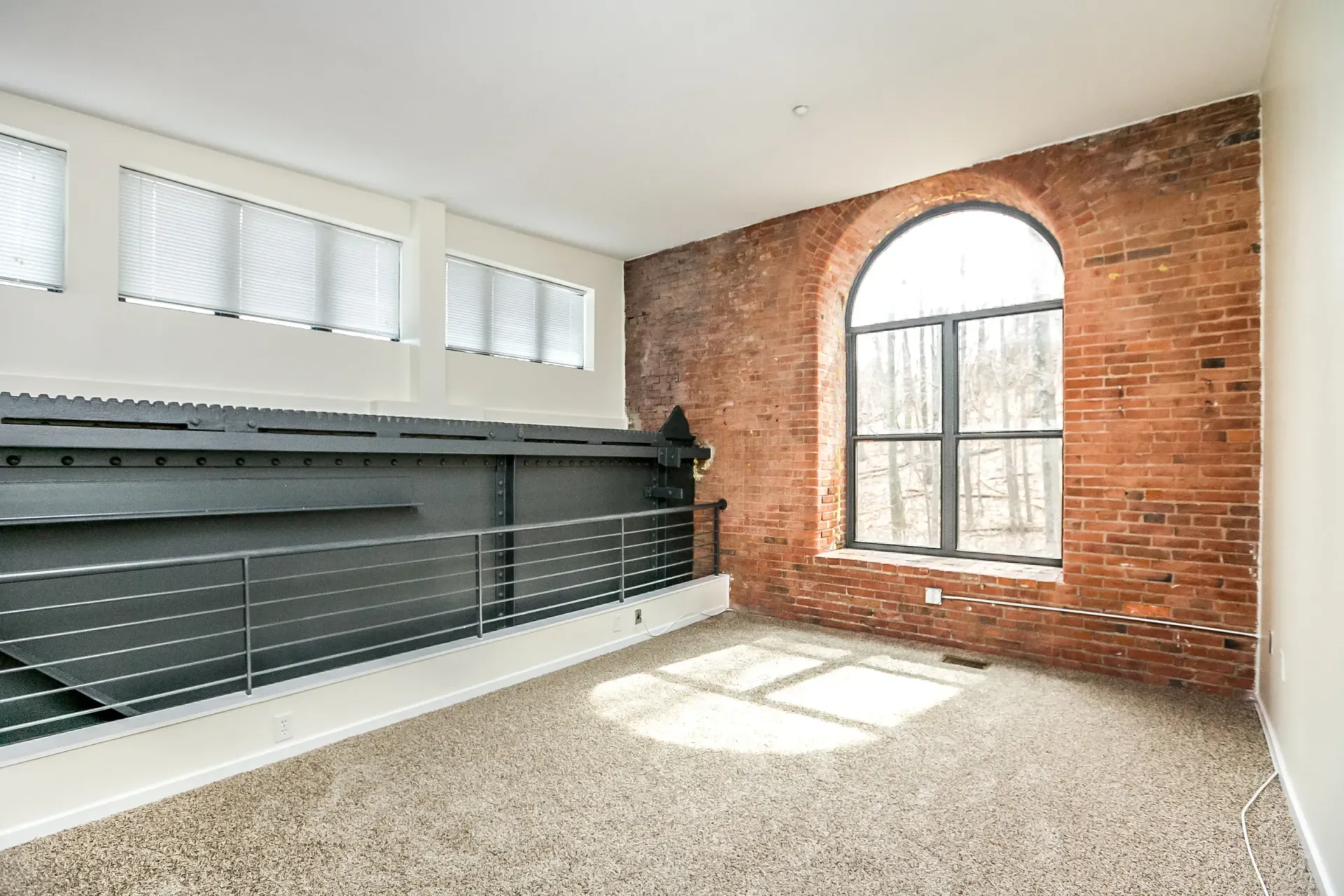 an empty room with a brick wall and a large window .