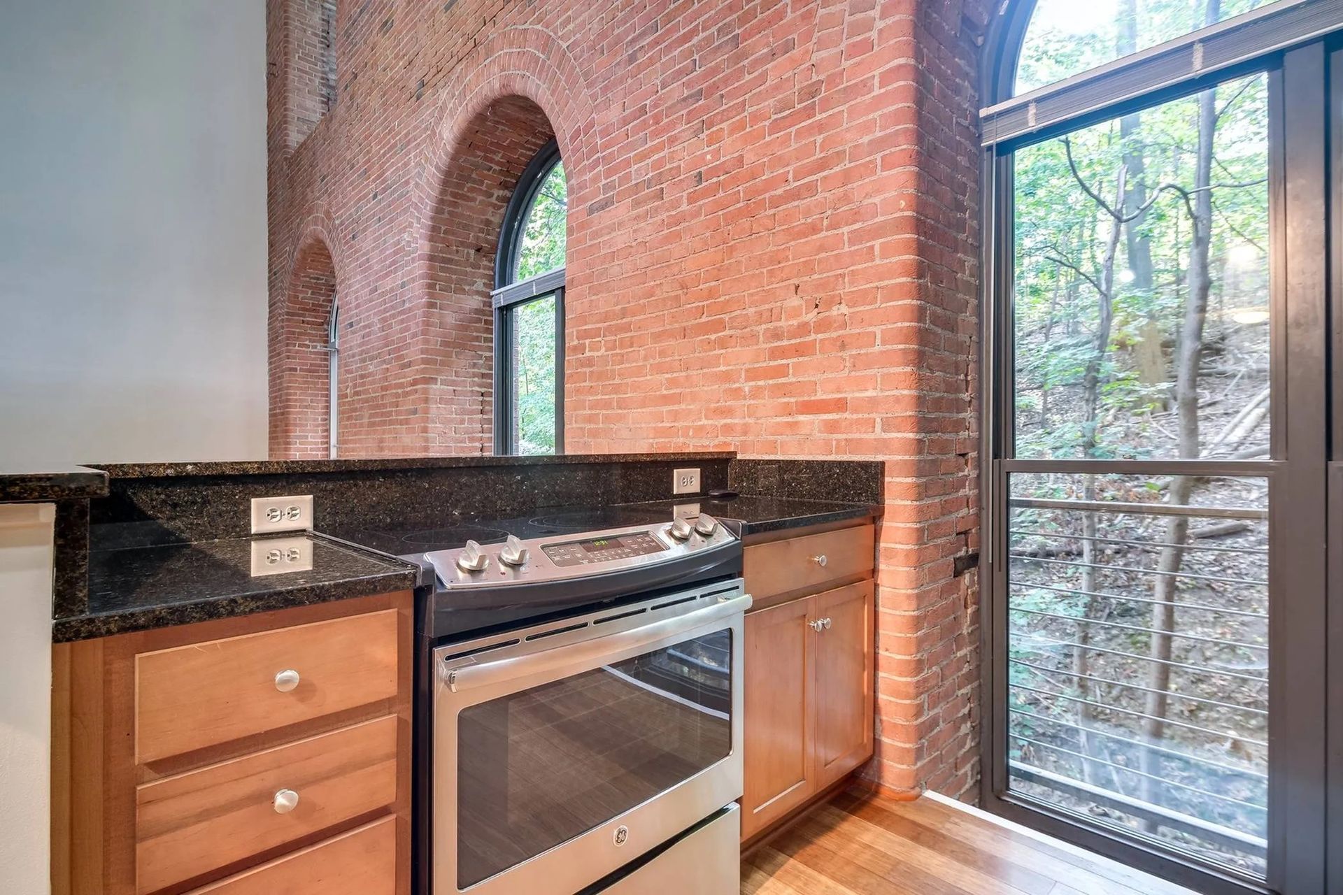 a kitchen with a stove , oven , cabinets and a brick wall .