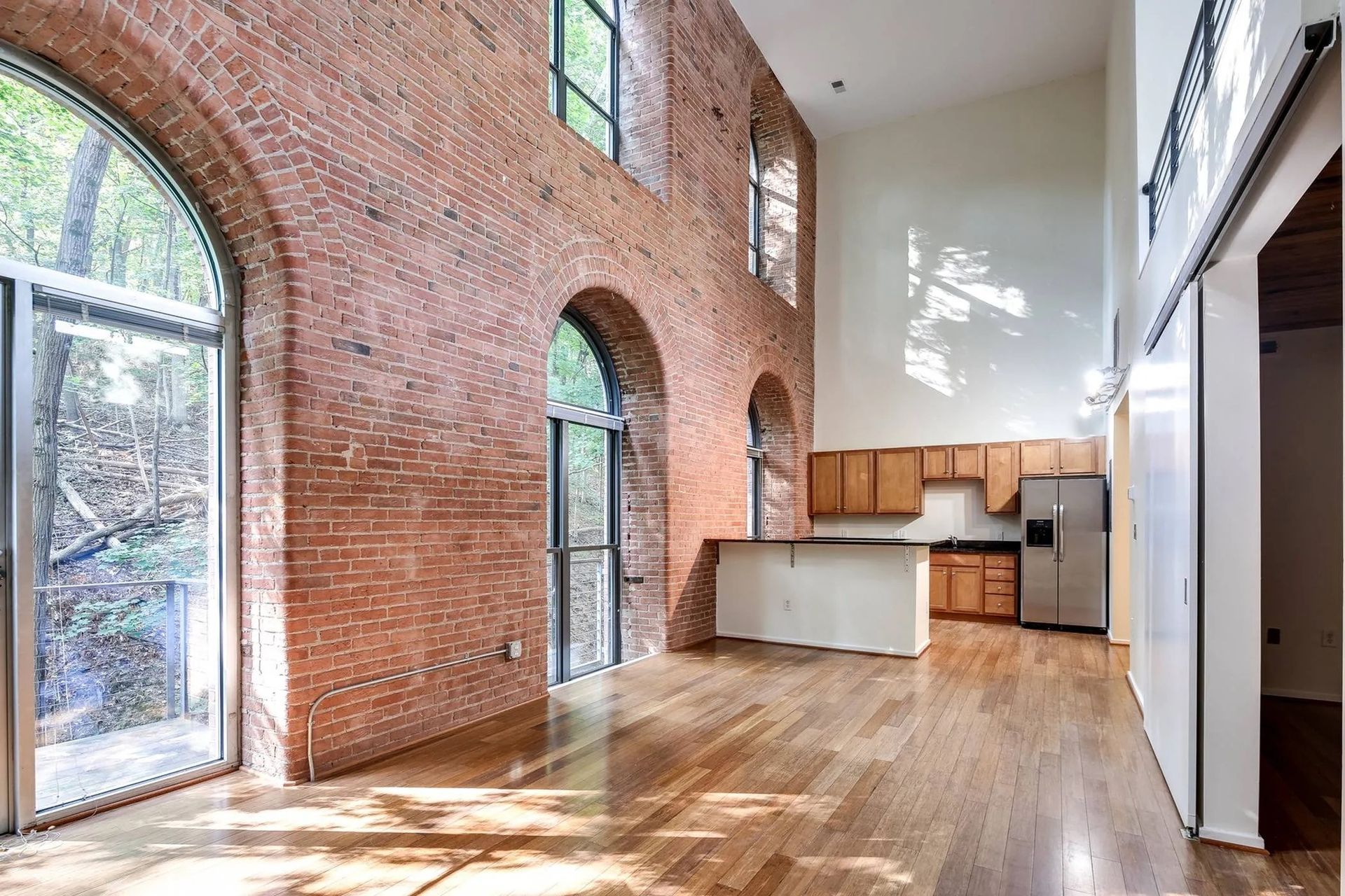 a large empty room with a brick wall and a kitchen