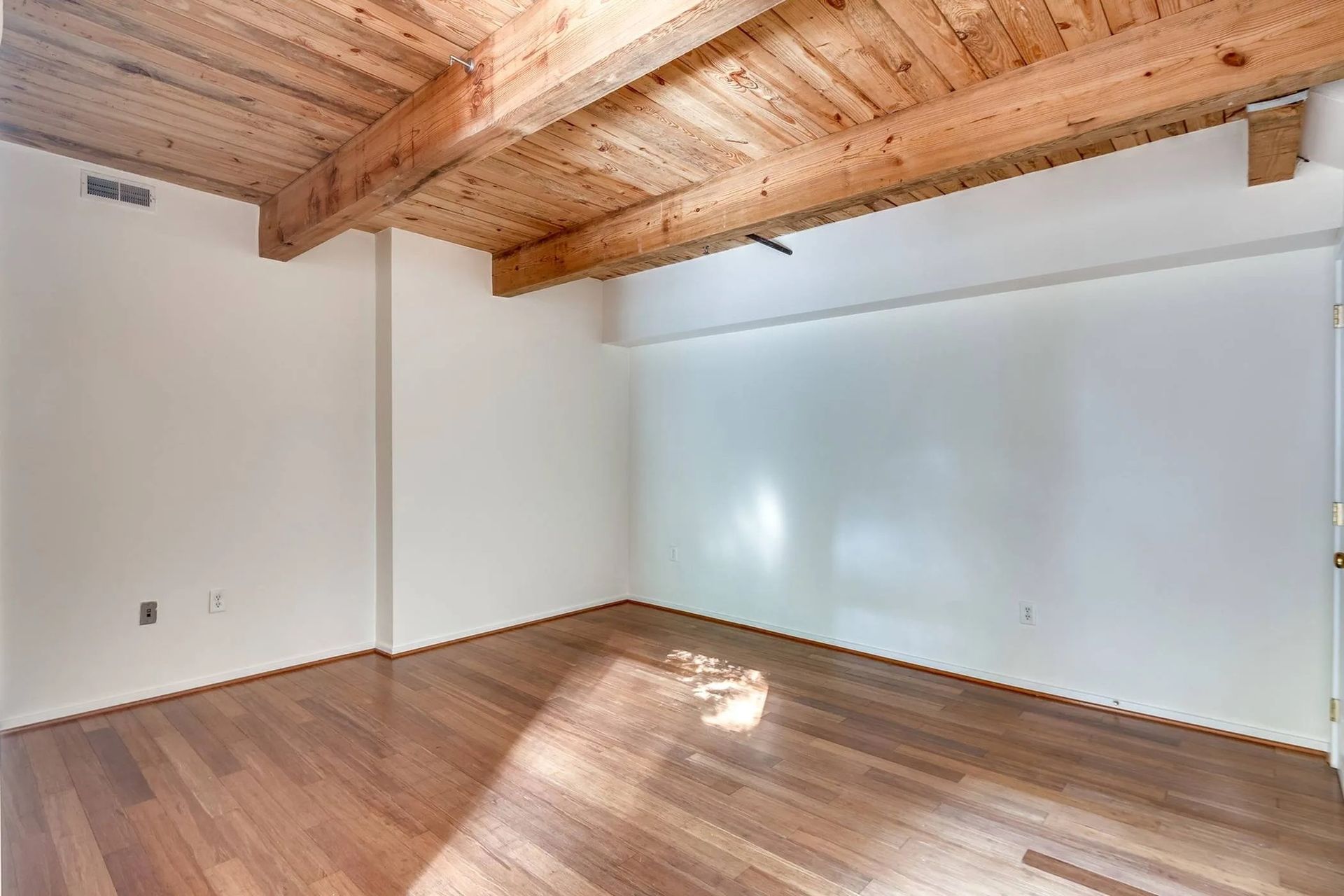 an empty room with wooden floors and a wooden ceiling .