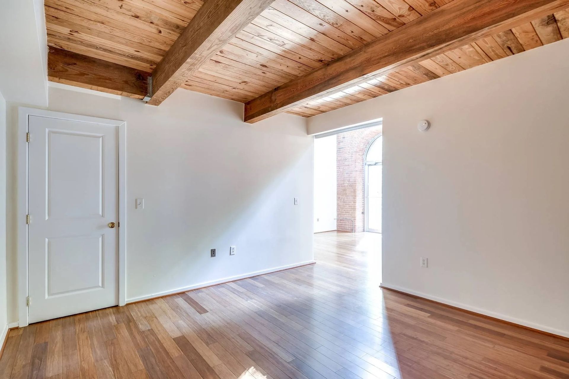 an empty room with hardwood floors and a wooden ceiling .