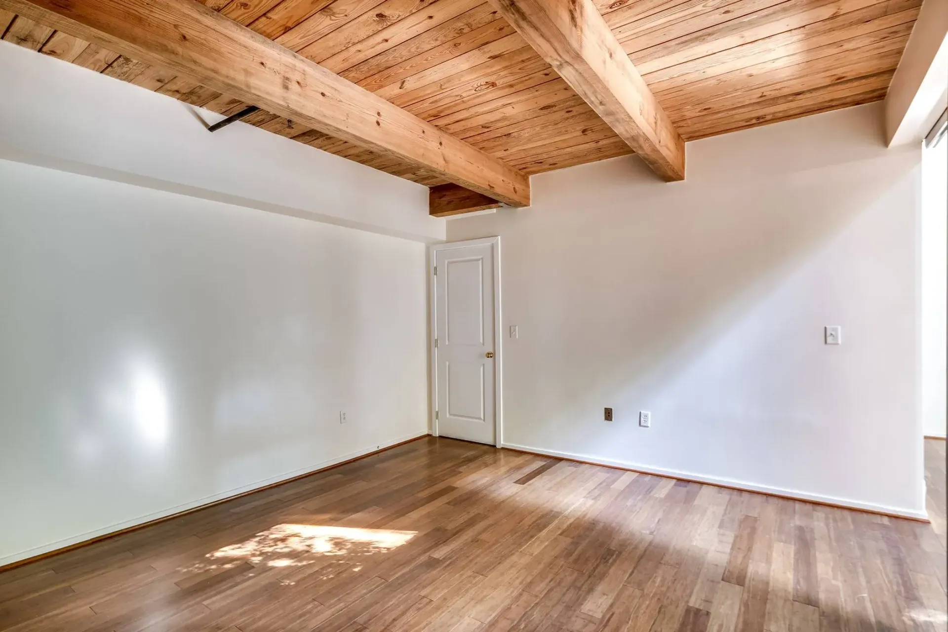 an empty room with hardwood floors and a wooden ceiling .