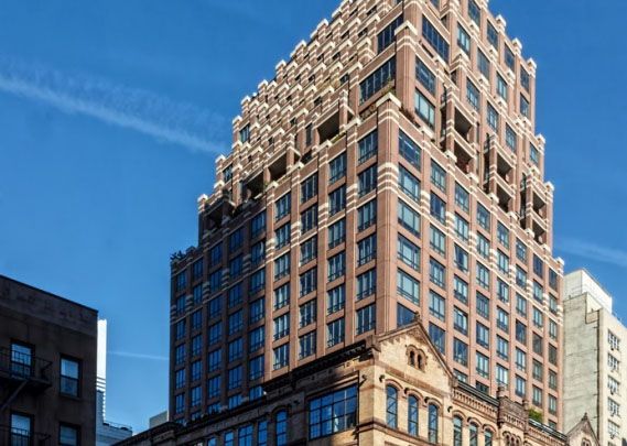 Tall brick building with many windows against a blue sky.