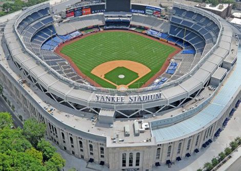 Aerial view of Yankee Stadium with green field, seating, and surrounding buildings.