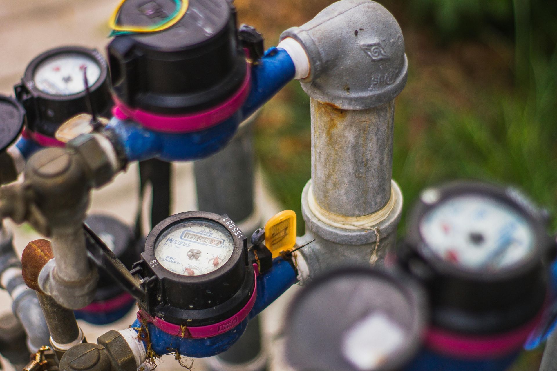 Close-up of water meters connected by pipes, showing gauges with numbers and a yellow handle.