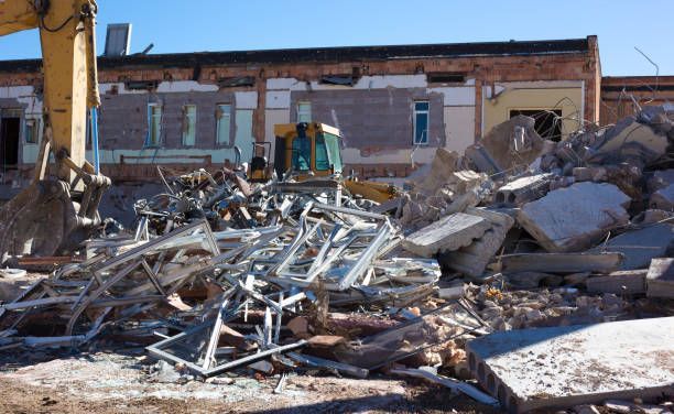 A bulldozer is demolishing a building with a pile of rubble in front of it