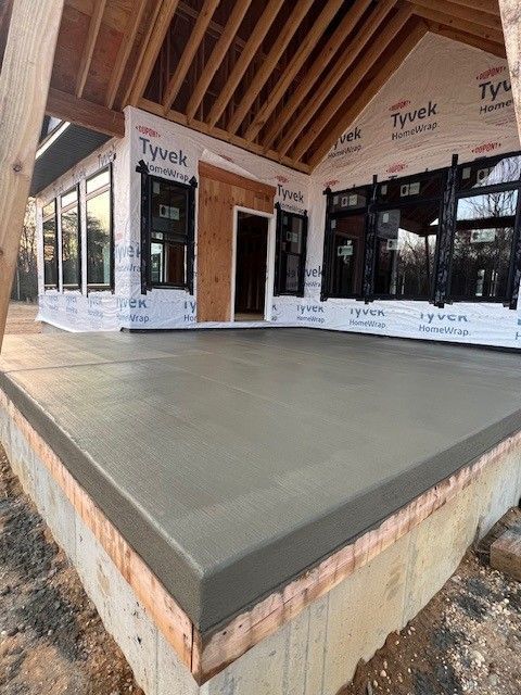 A concrete porch is being built in back of a house under construction