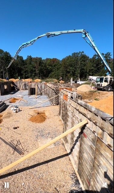 A concrete pump is being used to pour concrete on a house foundation
