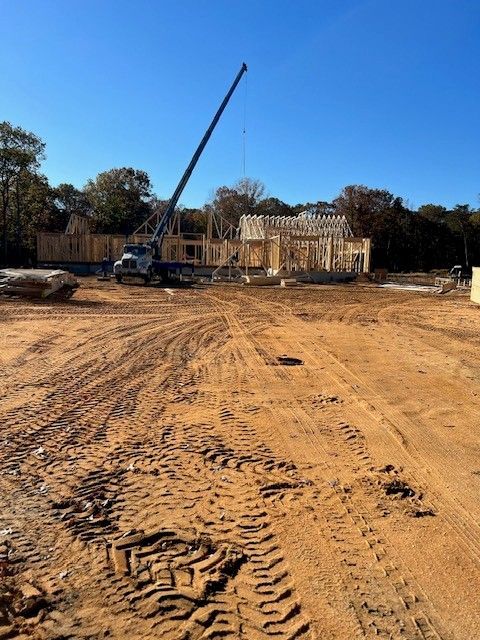 A construction site with a house being built with a crane in the background