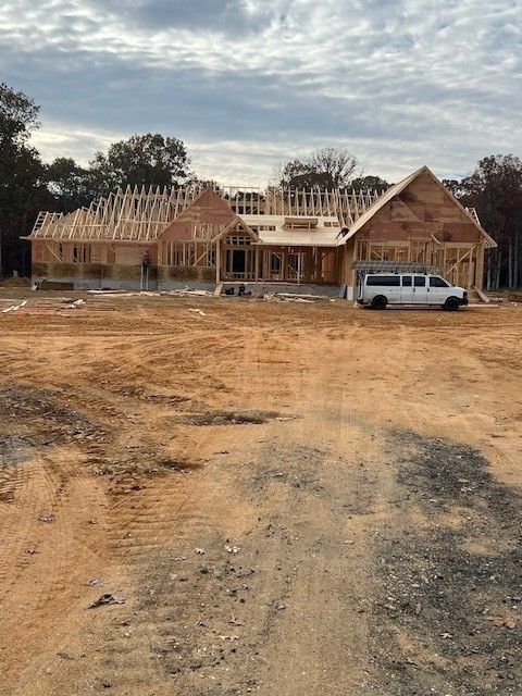 A white van is parked in front of a house under construction