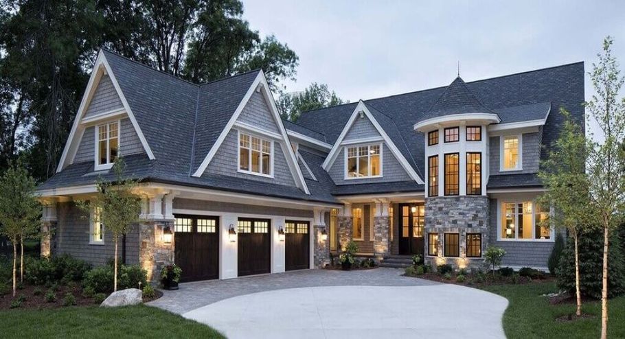 A large modern craftsman house with a lot of windows and a driveway in front of it